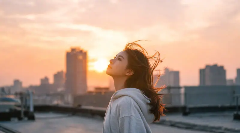 Woman looking up at a city skyline at golden hour